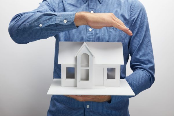 cropped-shot-of-man-holding-small-house-model-on-g-2024-11-17-21-22-56-utc
